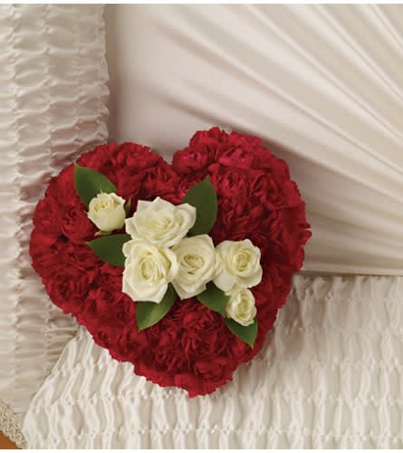 Heart-shaped red rose arrangement with white roses on a white cushion