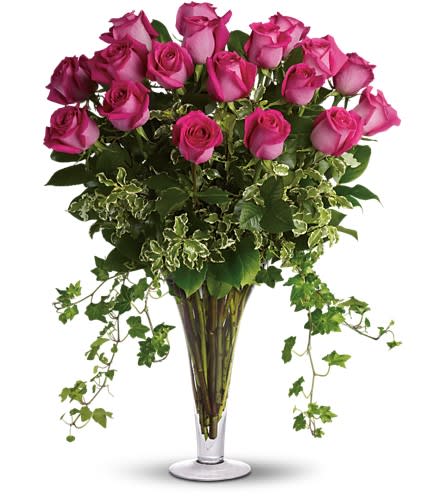 Pink roses arranged in a tall clear vase with trailing ivy