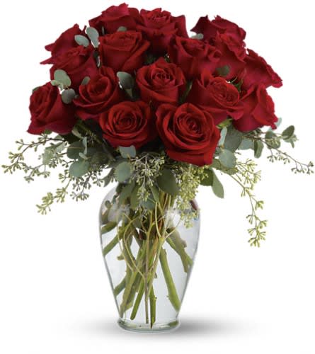 Red roses arranged in a clear glass vase with airy greenery