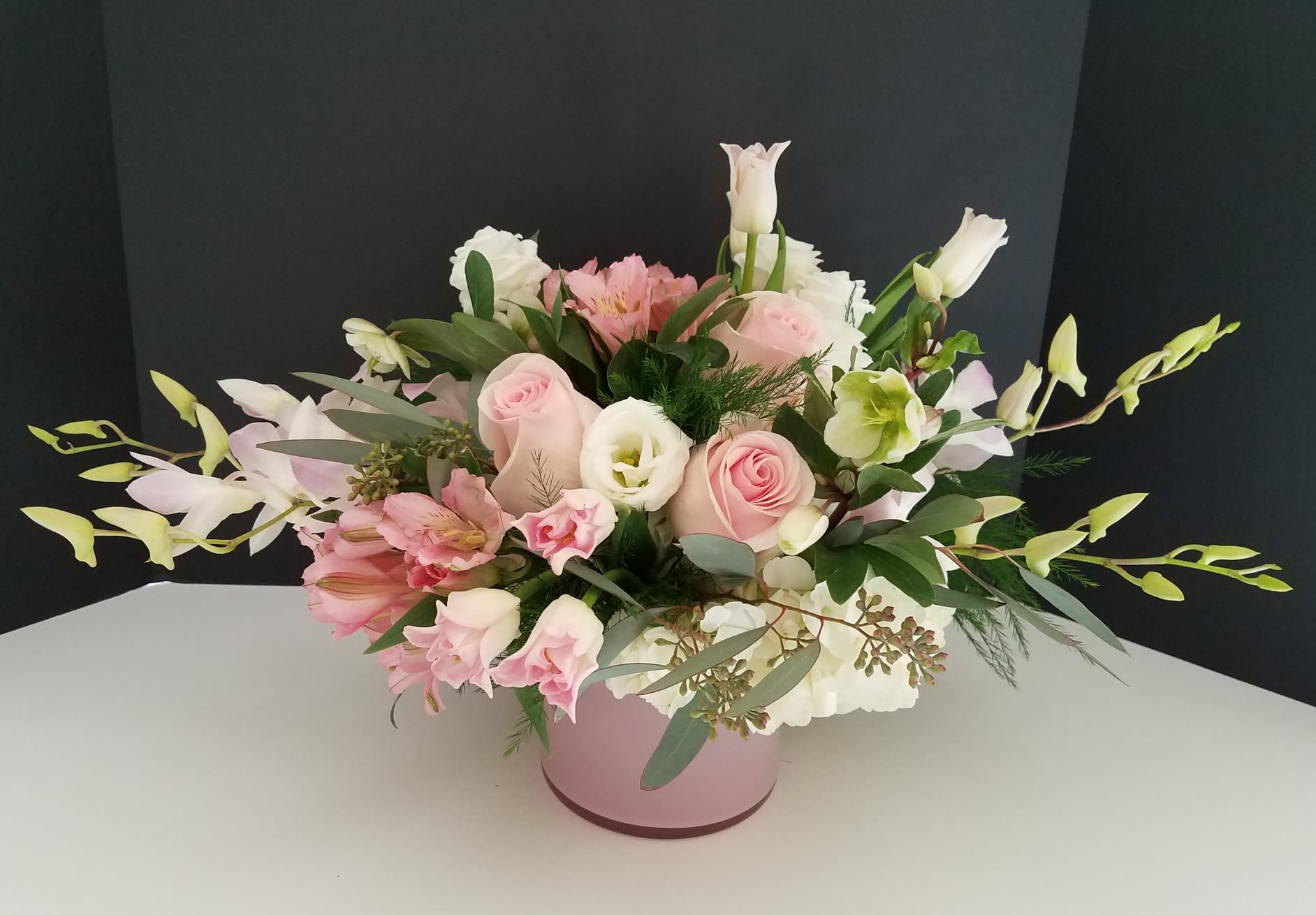 Pink and white mixed flower arrangement in a round pink box