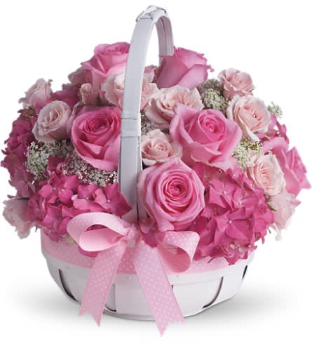 Pink roses and hydrangeas arranged in a white basket with a pink ribbon
