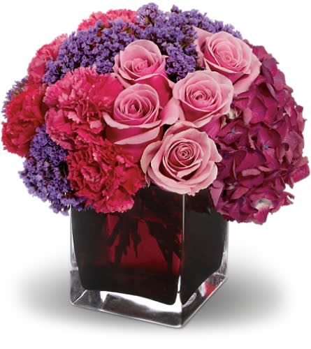 Pink roses and purple flowers arranged in a clear square vase