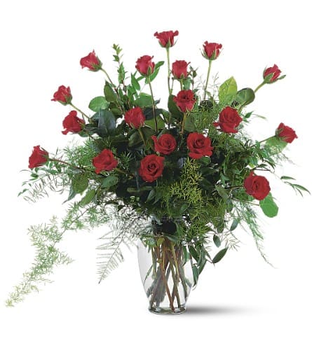 Red roses arranged in a clear glass vase with airy greenery