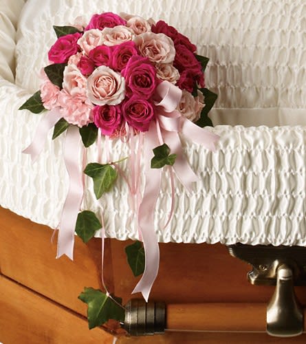 Pink and white rose bouquet with ribbon drapes on a casket