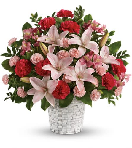 Pink lilies and carnations in a white woven basket