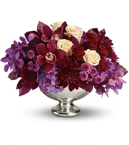Purple and burgundy floral arrangement in a silver pedestal vase