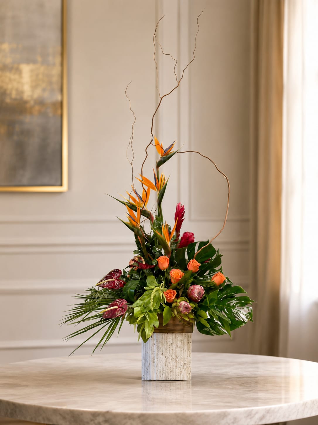 Tropical Eruption  - Orange birds of paradise thrust upward in a dramatic, asymmetrical silhouette-the perfect focal point for a tropical flower arrangement made to celebrate Mother's Day, a bold birthday, or to brighten a modern home. This flower arrangement for special occasions like a summer wedding, anniversary, or Easter mixes tropical flair with romantic notes so the person you're thinking of will feel noticed and celebrated.  Nestled in a square stone-look container, the composition layers curly branches and tall vertical lines over clusters of orange roses, pink protea, and other tropical blooms. Glossy green foliage grounds the vivid palette of orange, pink, purple and yellow for an energetic, contemporary look that also reads as warm and thoughtful. The container's clean, architectural shape makes this piece suitable as a housewarming gift, office centerpiece for a retirement or promotion, or a striking sympathy arrangement when a brighter touch is desired.  Sized to command attention without overwhelming a table, the arrangement is designed for easy display and no-fuss care-keep it in fresh water, out of direct heat, and trim stems if needed to extend life. It's an ideal "just because" present, a confident expression of love and romance, and a festive choice for holidays from Christmas to Fourth of July when you want a show-stopping floral statement.