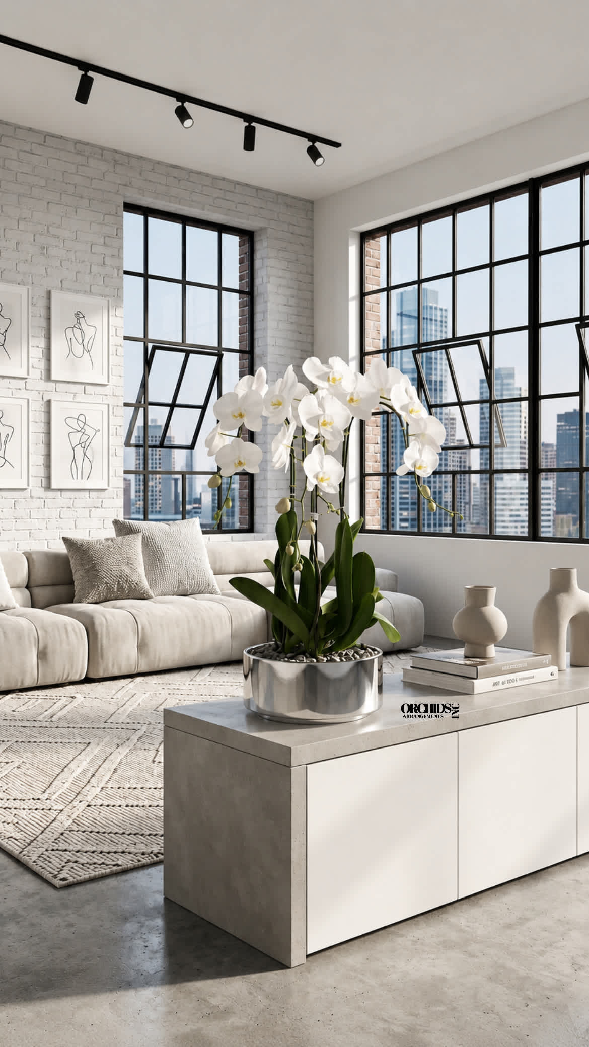 White orchid arrangement in a silver pot on a table