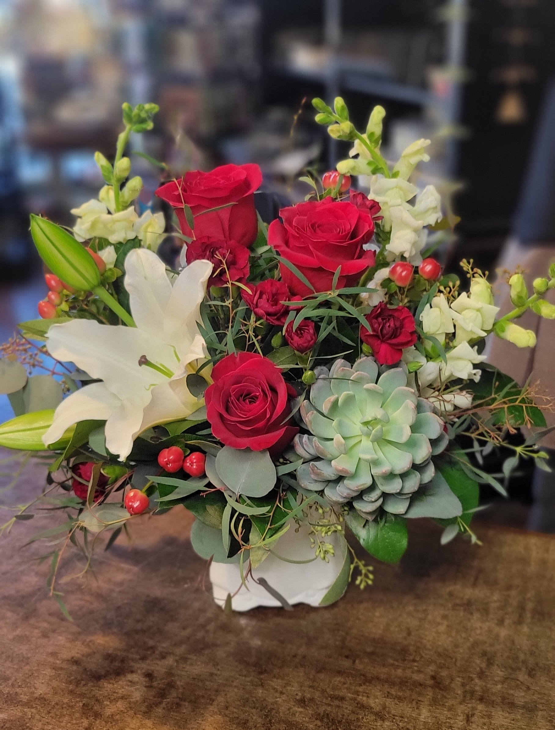 Bouquet of red roses and white lilies with a succulent in a white vase