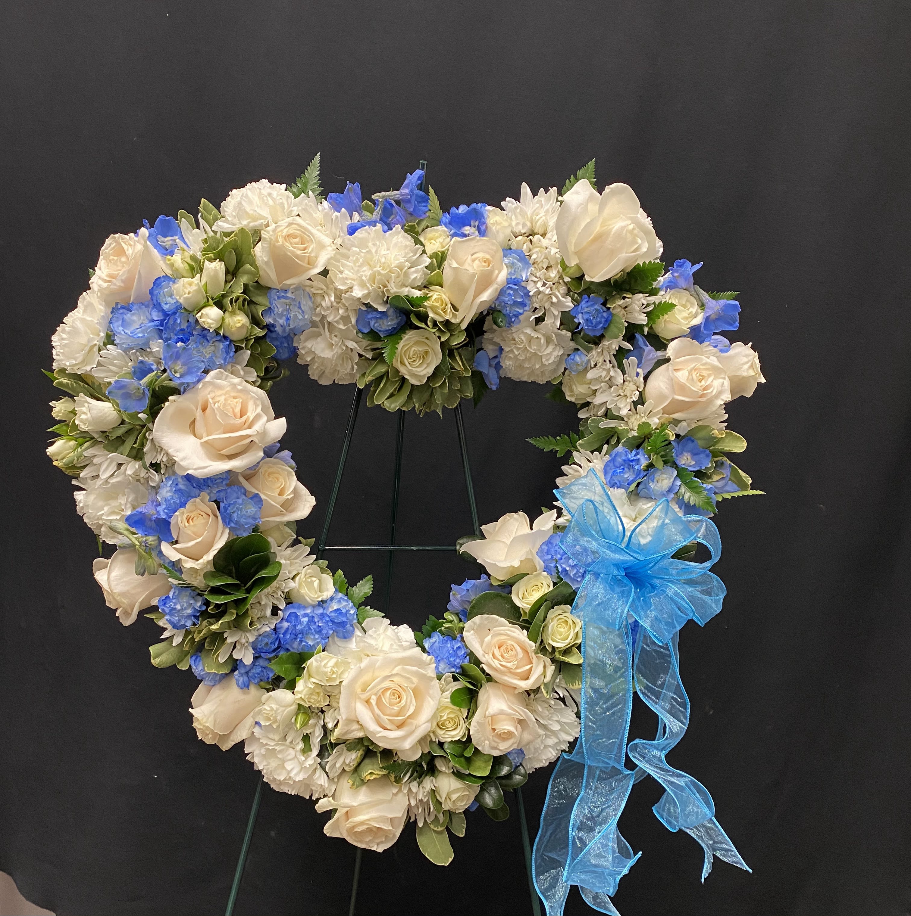 Heart-shaped floral wreath with cream roses, white blooms, and blue flowers