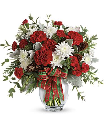 Red and white flowers arranged in a clear glass vase with a plaid ribbon