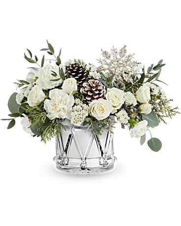 White floral arrangement in a clear glass vase with pinecones