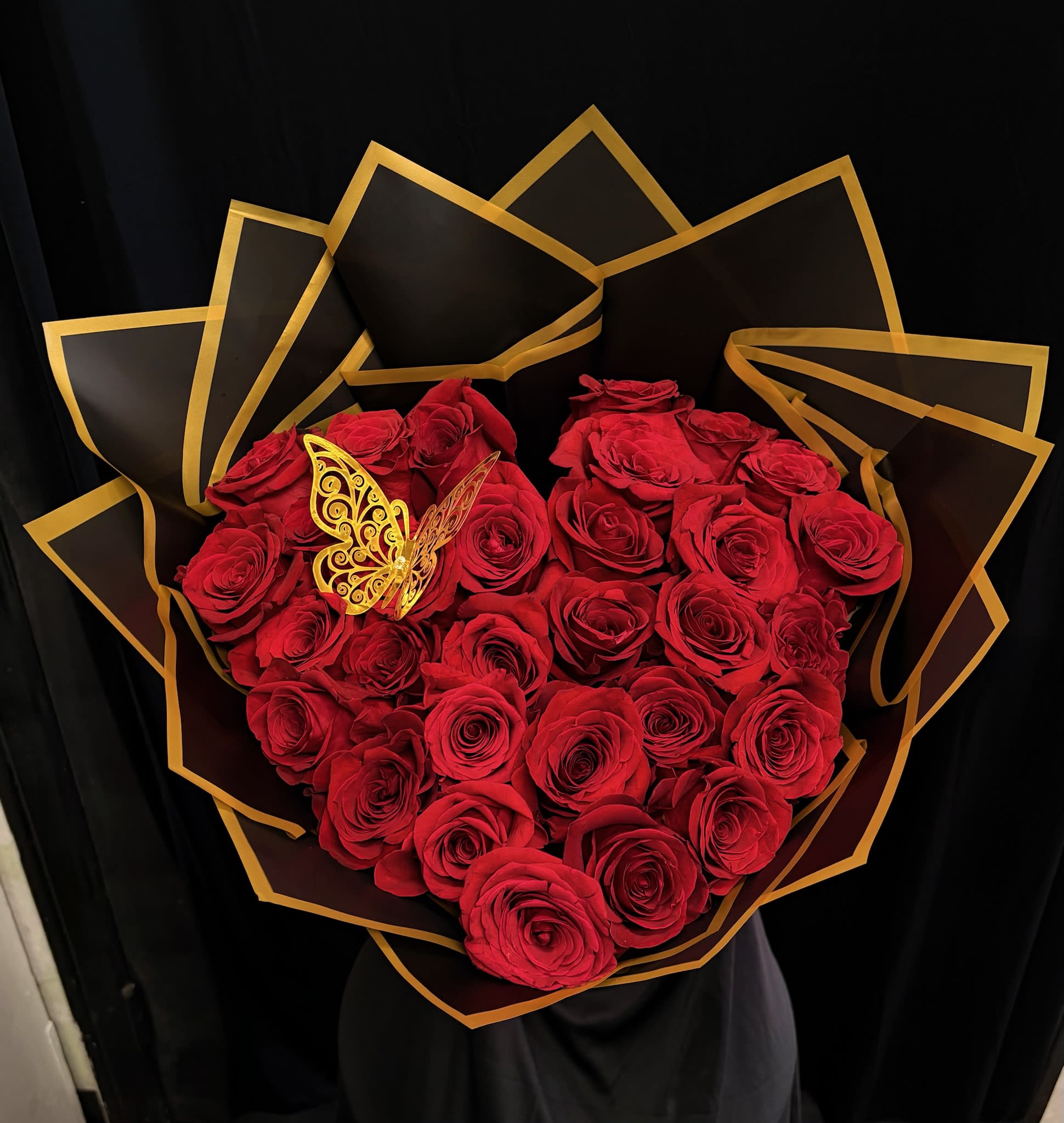 Heart-shaped bouquet of red roses with black and gold wrapping