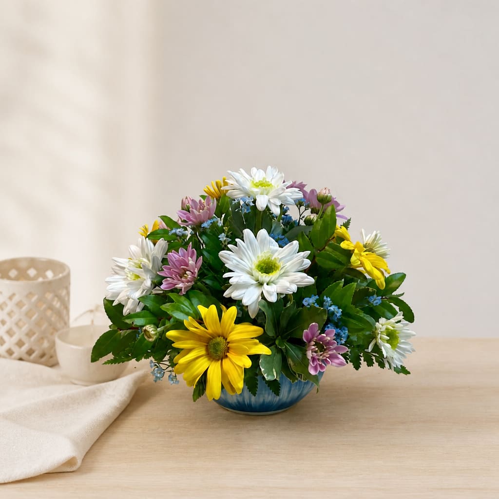Mixed daisy bouquet in a blue bowl vase on a table