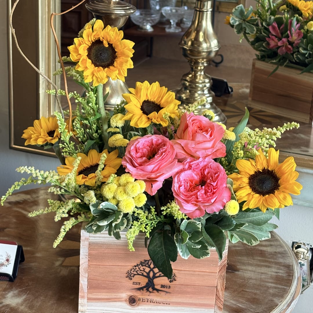 Pink roses and sunflowers arranged in a wooden box