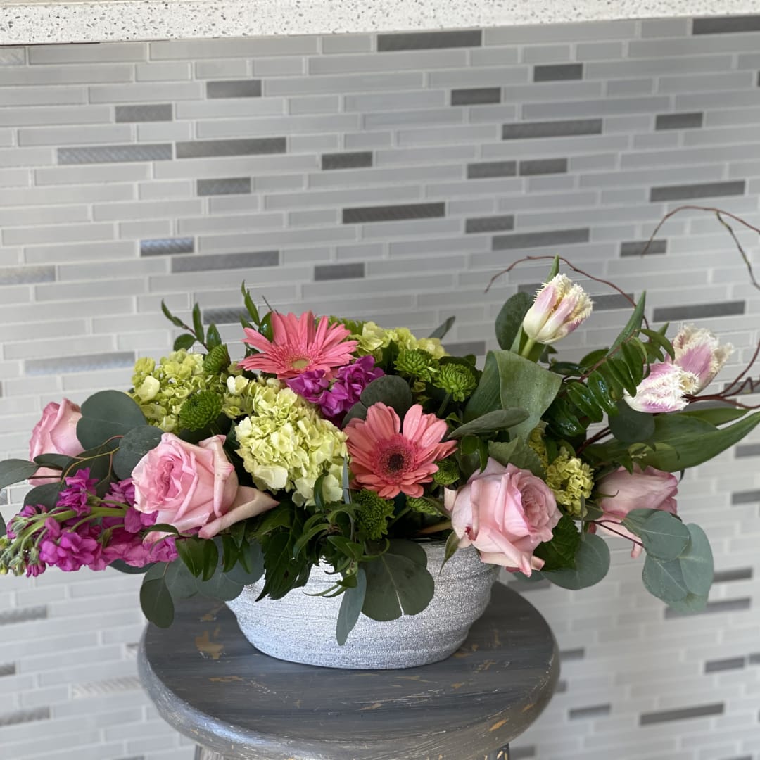 Pink roses and gerbera daisies arranged in a silver bowl vase