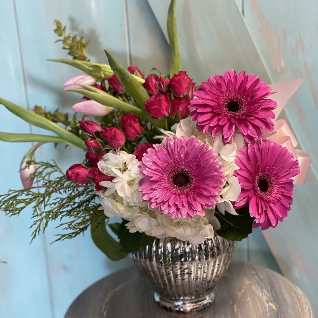 Pink gerbera daisies and roses in a silver vase