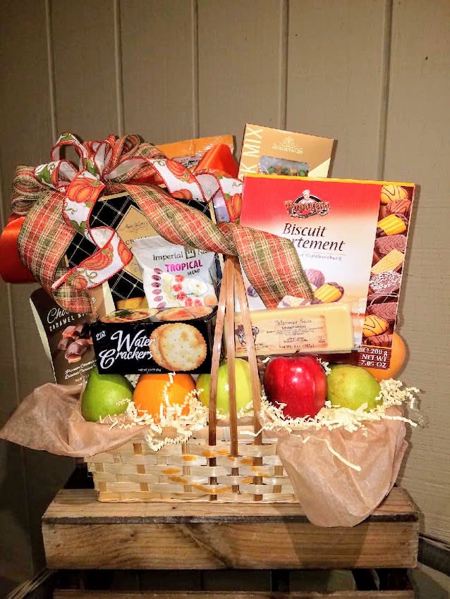 Gift basket with fruit and assorted snack boxes tied with a large ribbon
