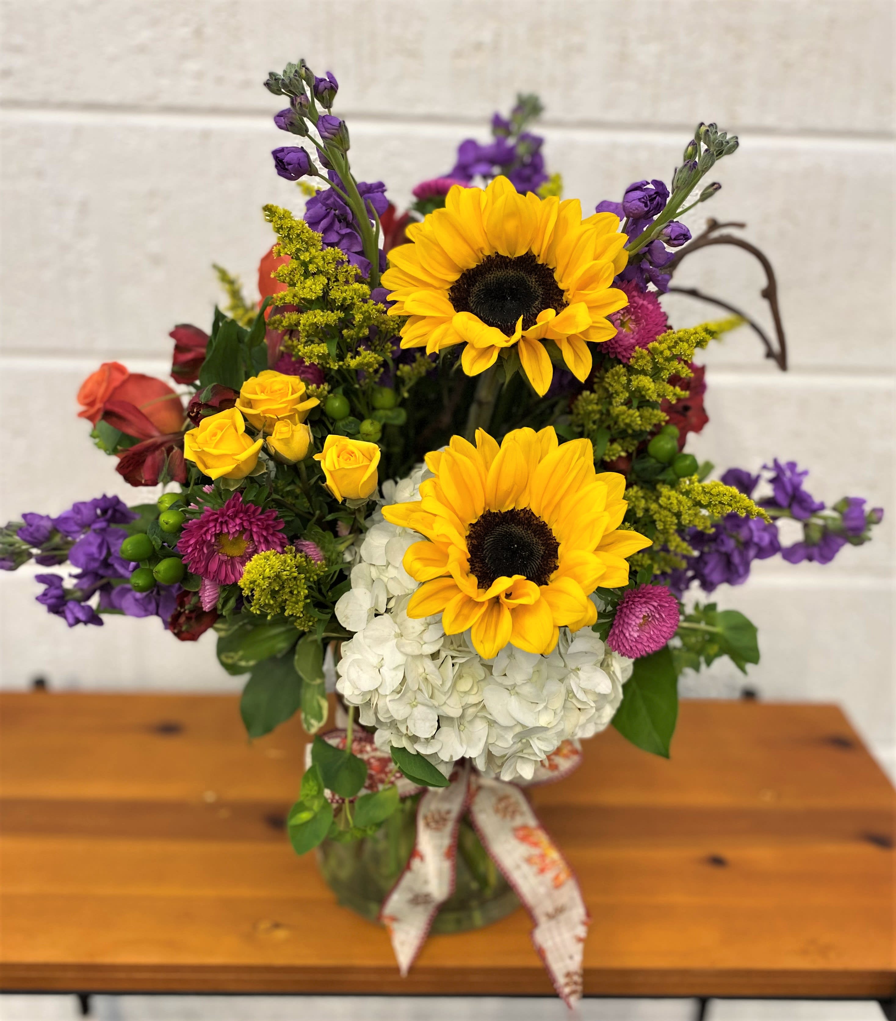 The Autumn Sun - Mix of Fresh Blooms designed in a large gathering vase accented with fall bow. 