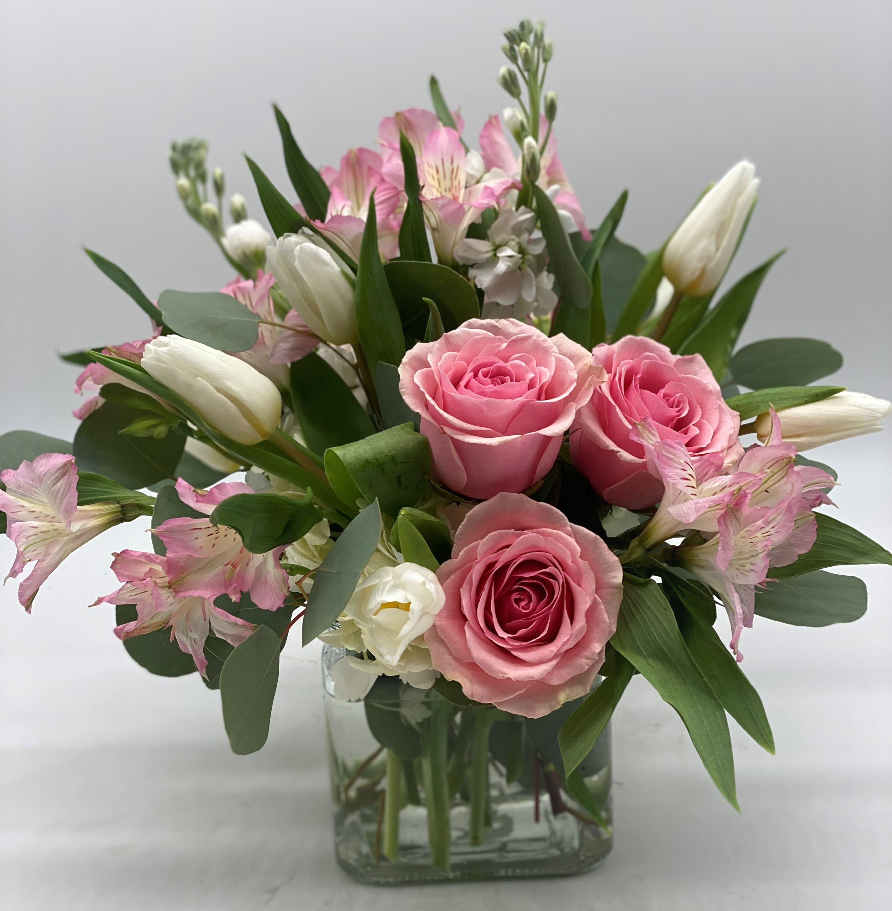 Pink roses and white tulips in a clear glass vase