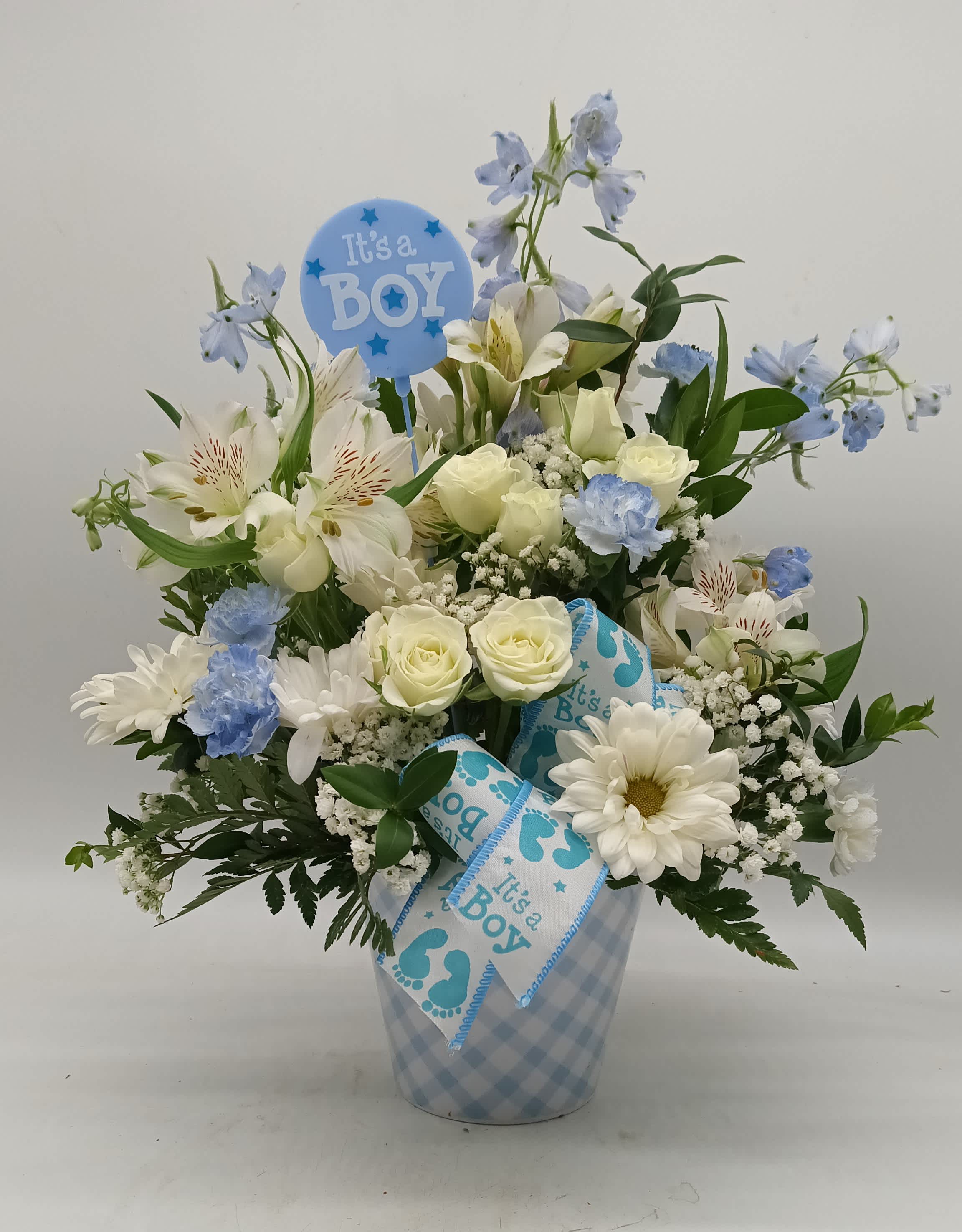 Blue and white flower arrangement in a checkered vase with a baby boy pick