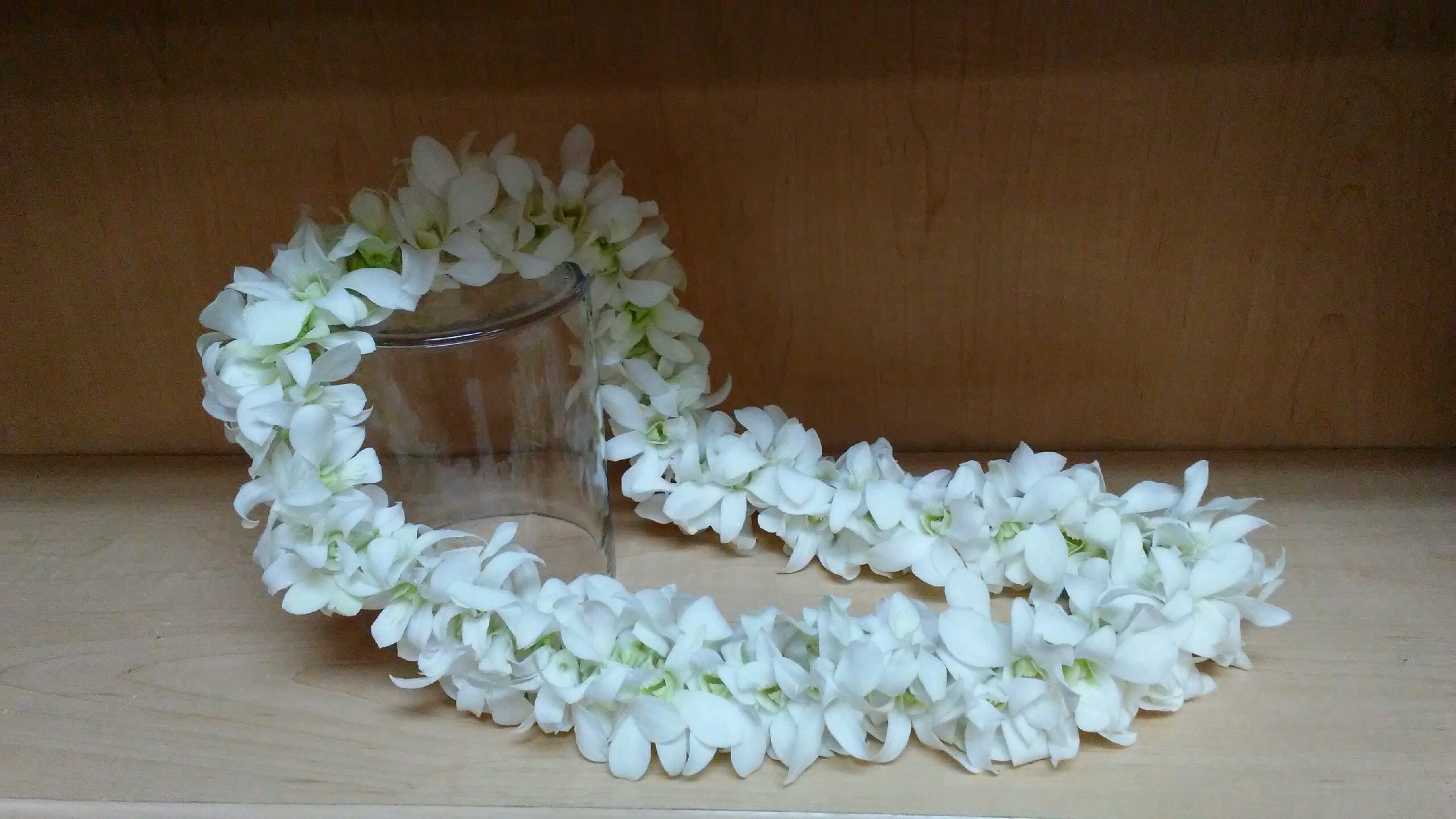 White flower lei draped around a clear glass jar