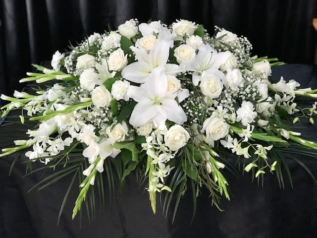 White floral casket spray with lilies and roses