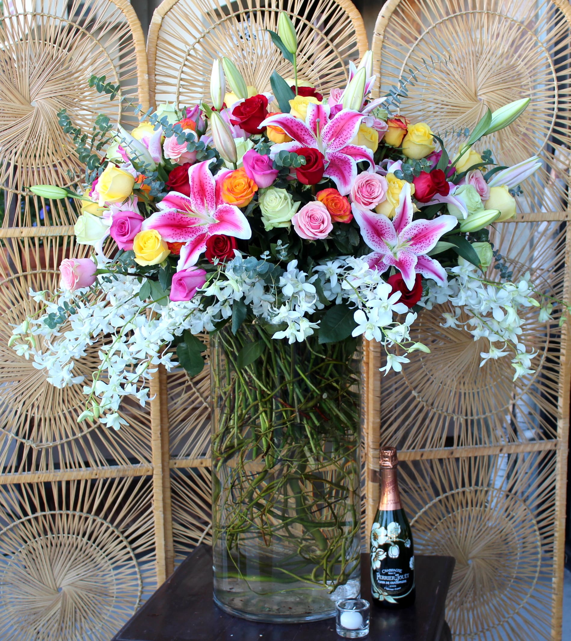Mixed bouquet of roses and lilies in a tall glass vase