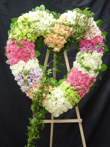 Heart-shaped floral wreath on an easel with pastel roses and hydrangeas