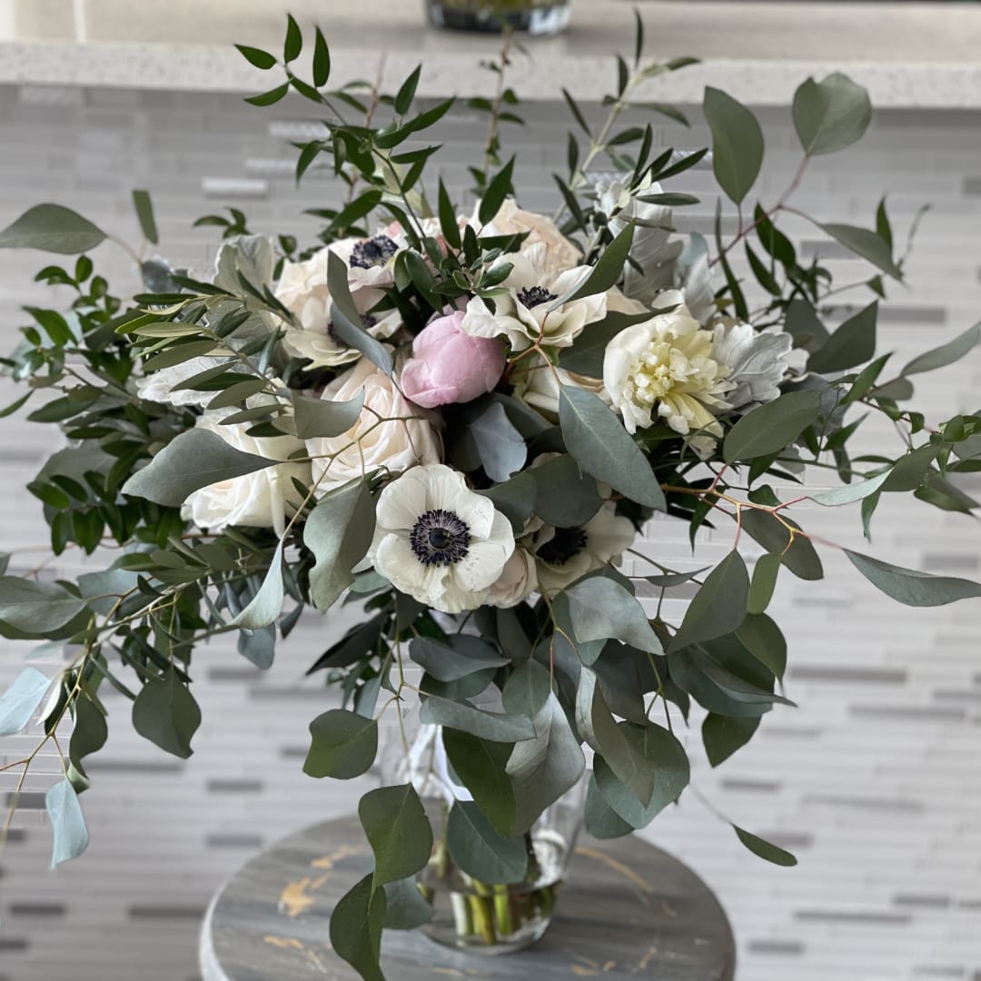 White and blush bouquet with dark-centered blooms in a clear glass vase