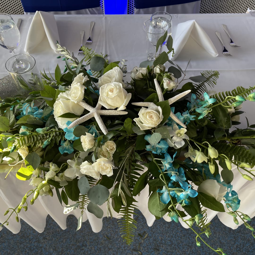 White rose centerpiece with blue orchids and starfish on a banquet table