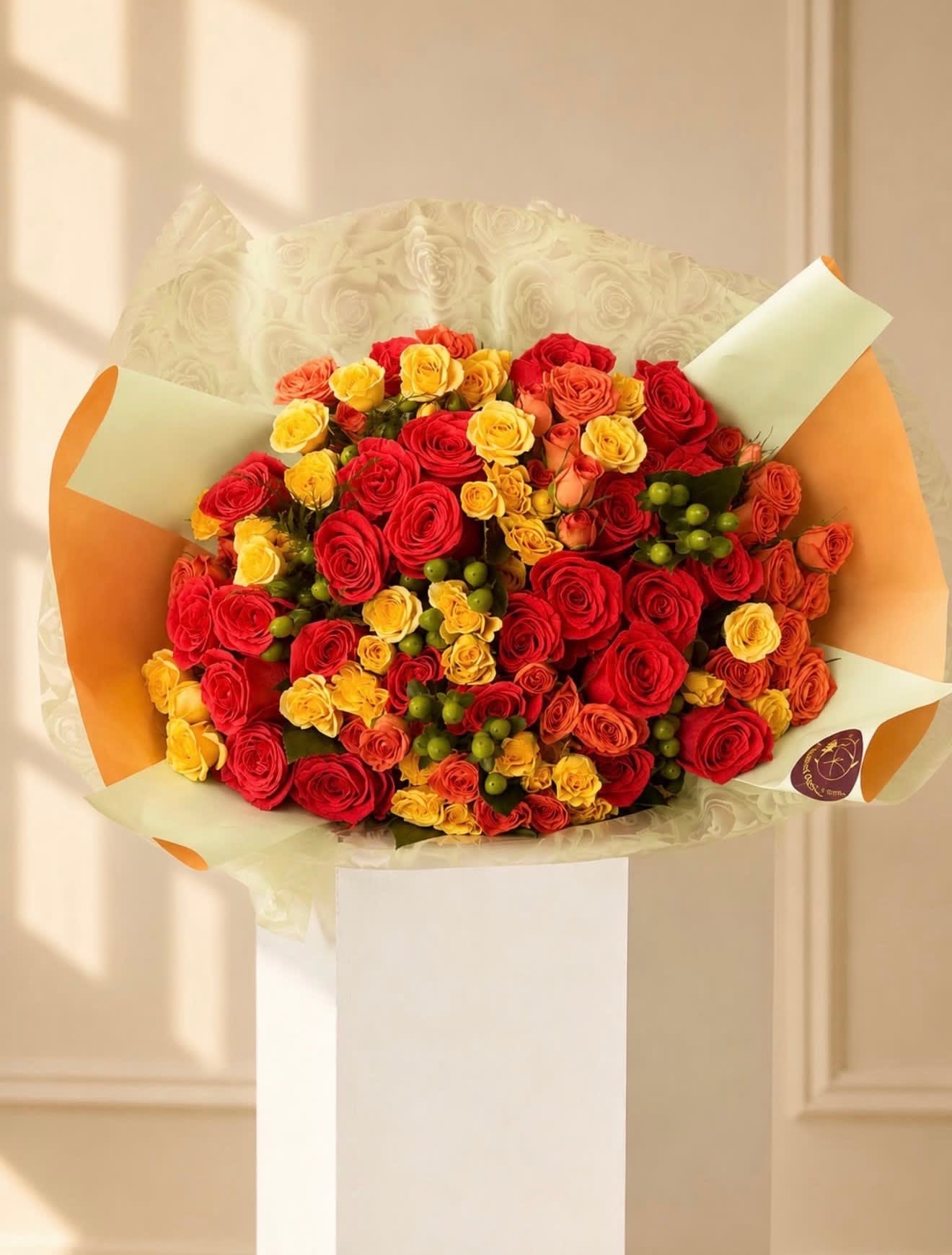 Bouquet of red, yellow, and orange roses wrapped in cream and orange paper