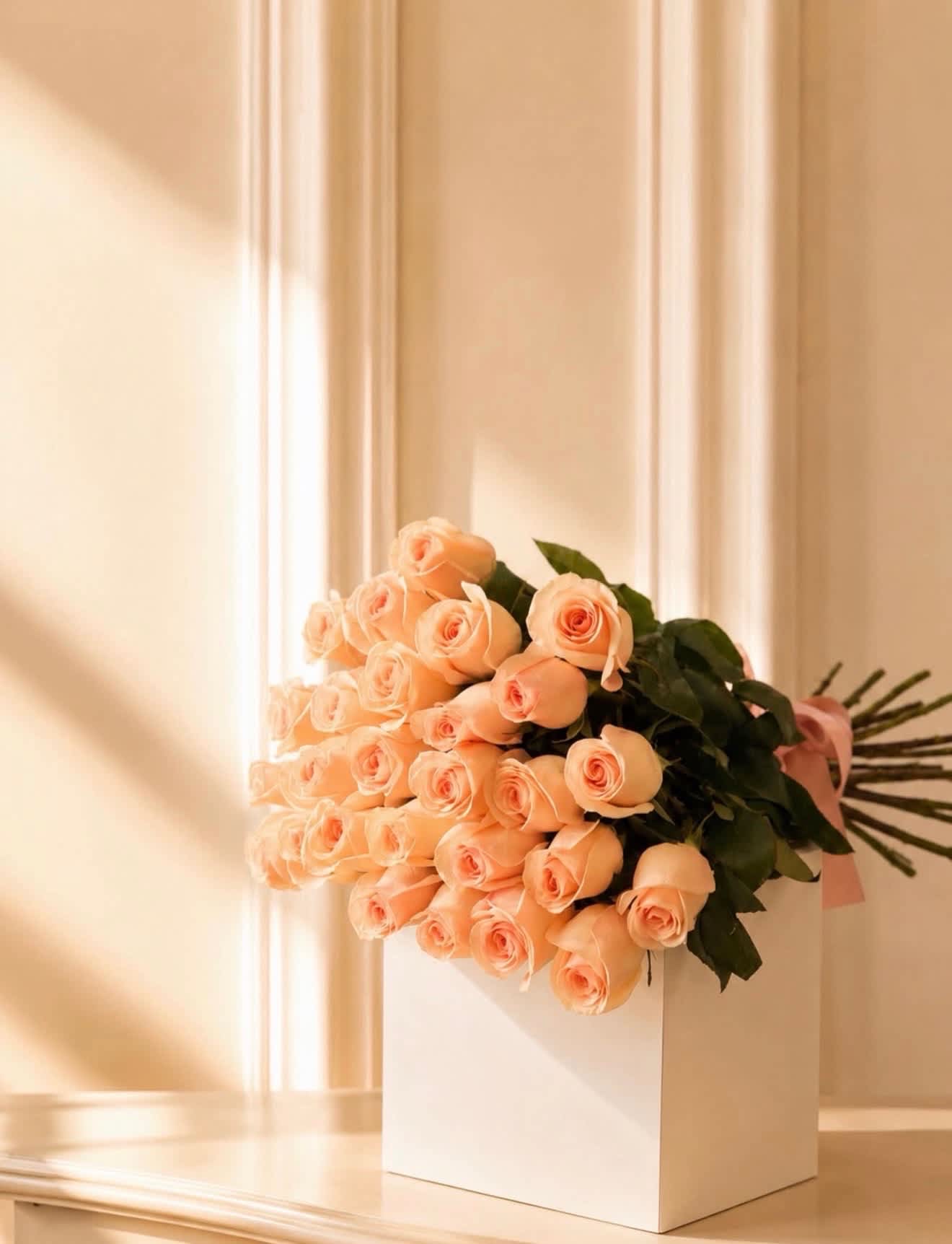 Bouquet of peach roses in a white box with a pink ribbon