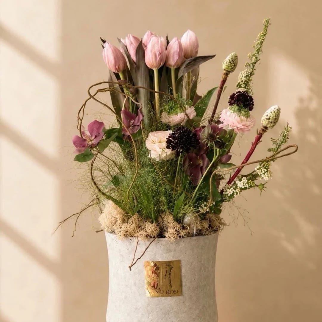 Pink tulips and mixed flowers arranged in a white vase
