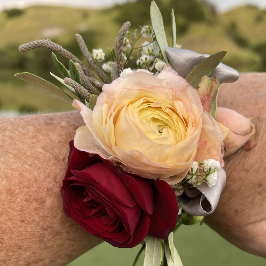 Two rose wrist corsages with ribbon and small white filler flowers