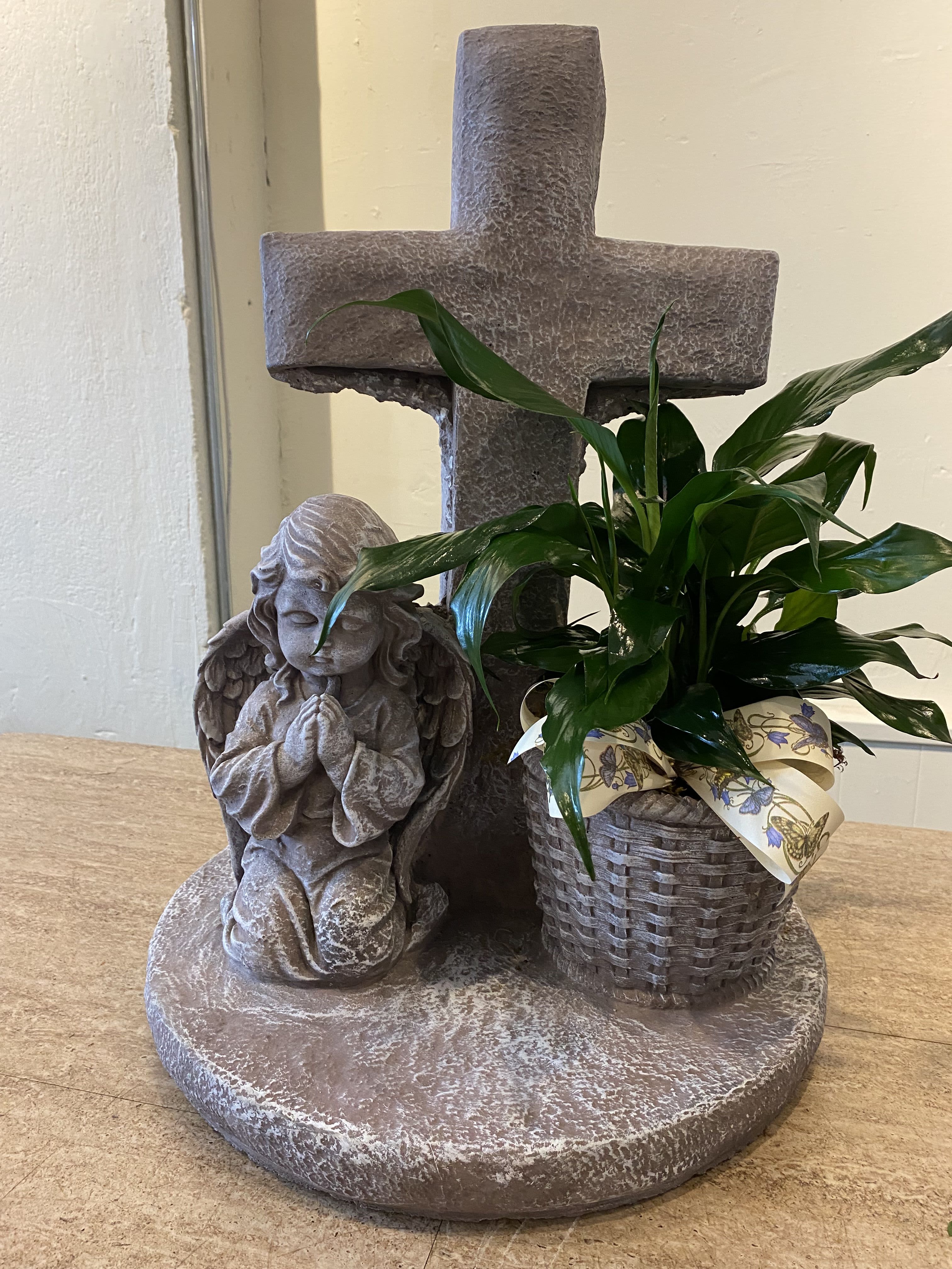 Potted green plant beside a stone cross and angel statue