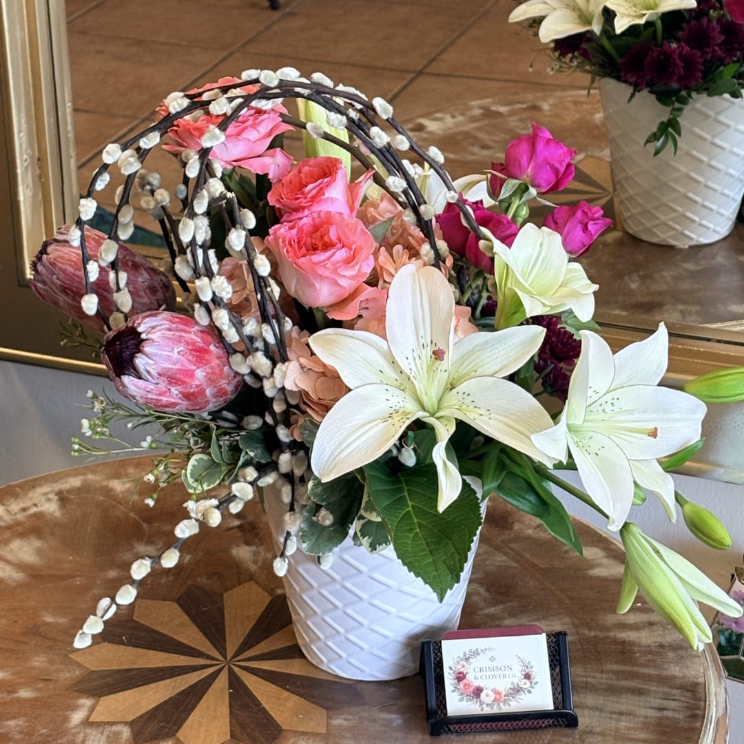 Mixed bouquet with white lilies, pink roses, and protea in a white vase