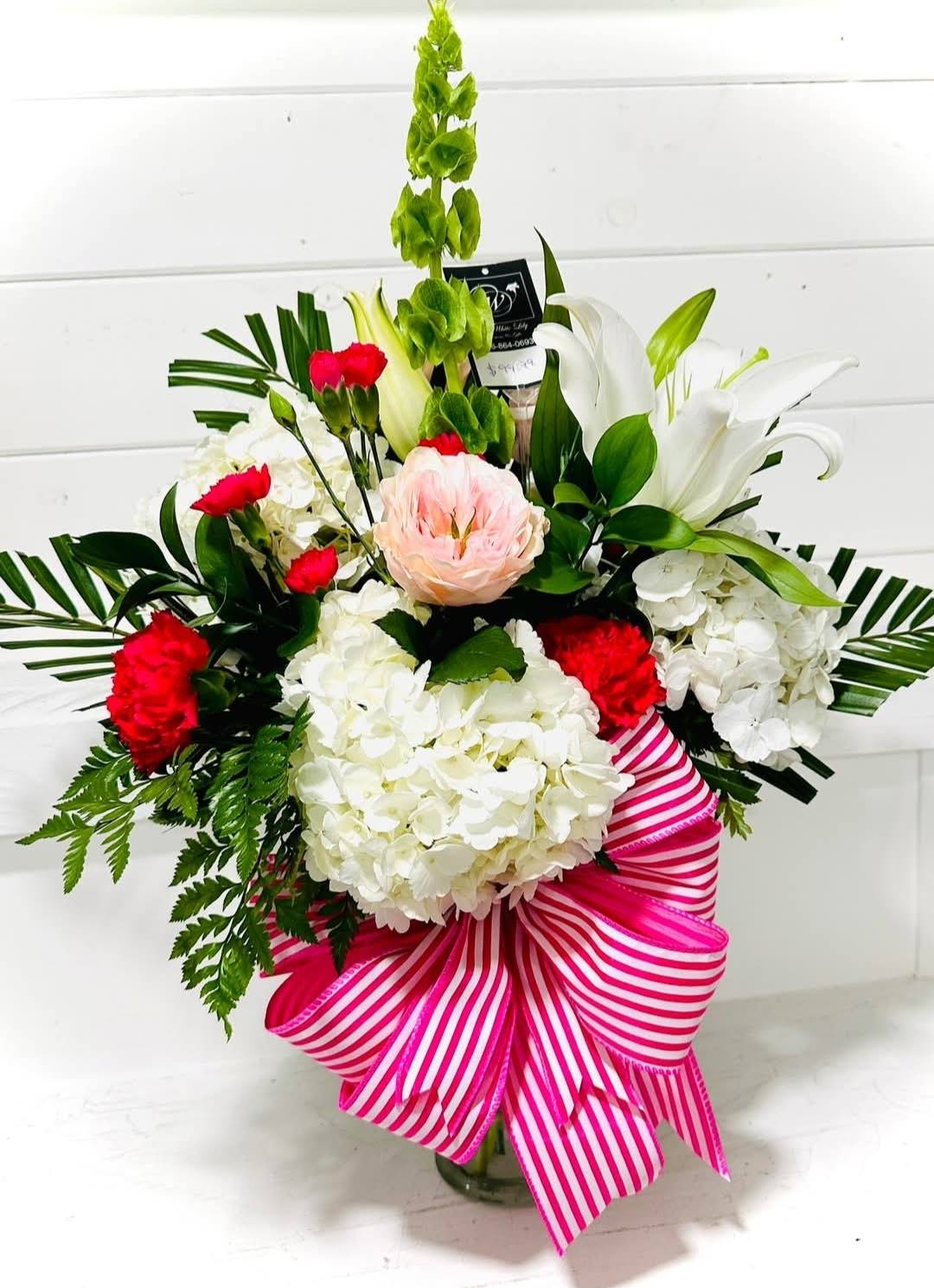Bouquet of white lilies, hydrangeas, and red carnations with a pink striped ribbon