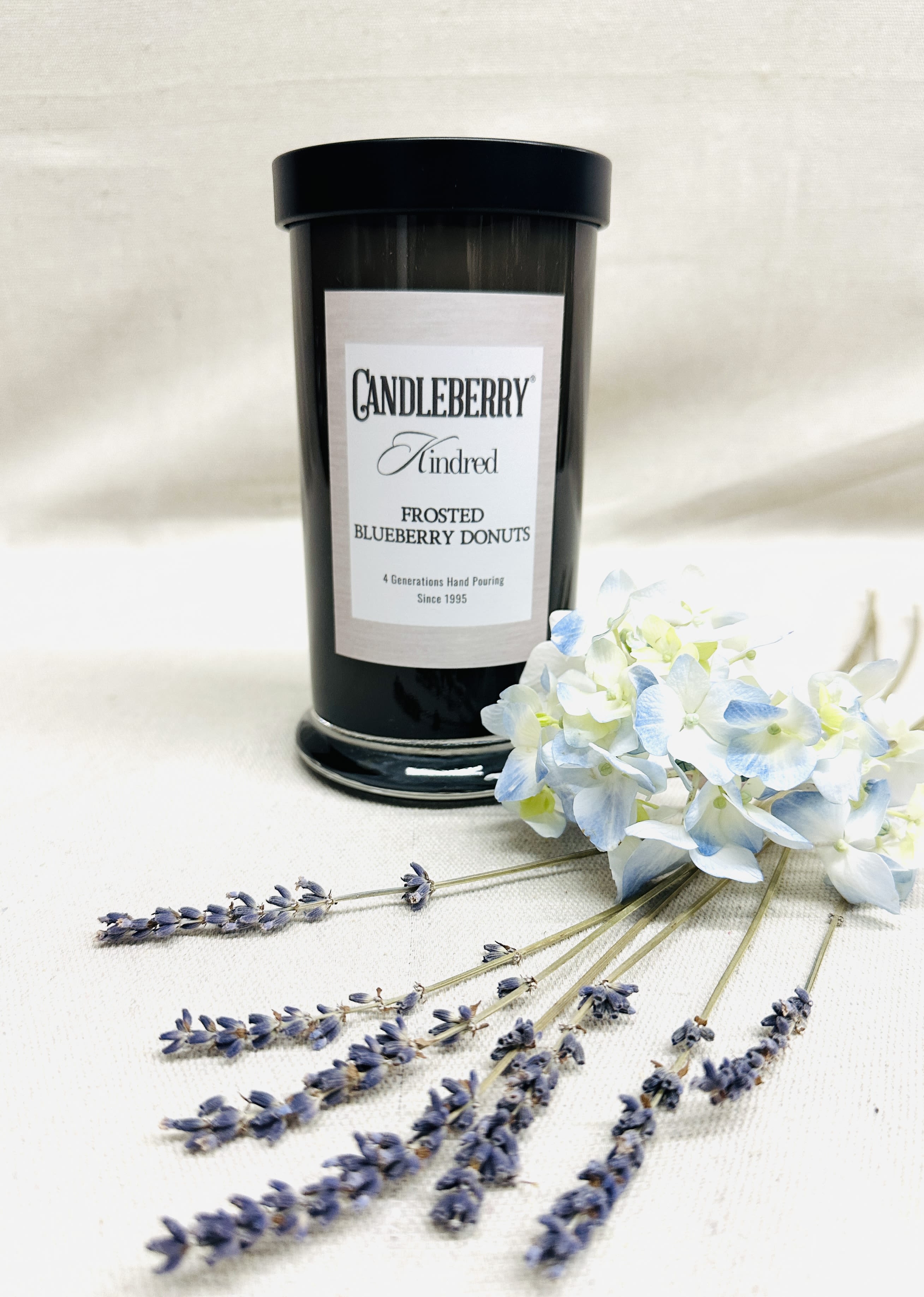 Black candle jar with a bouquet of pale blue and white flowers