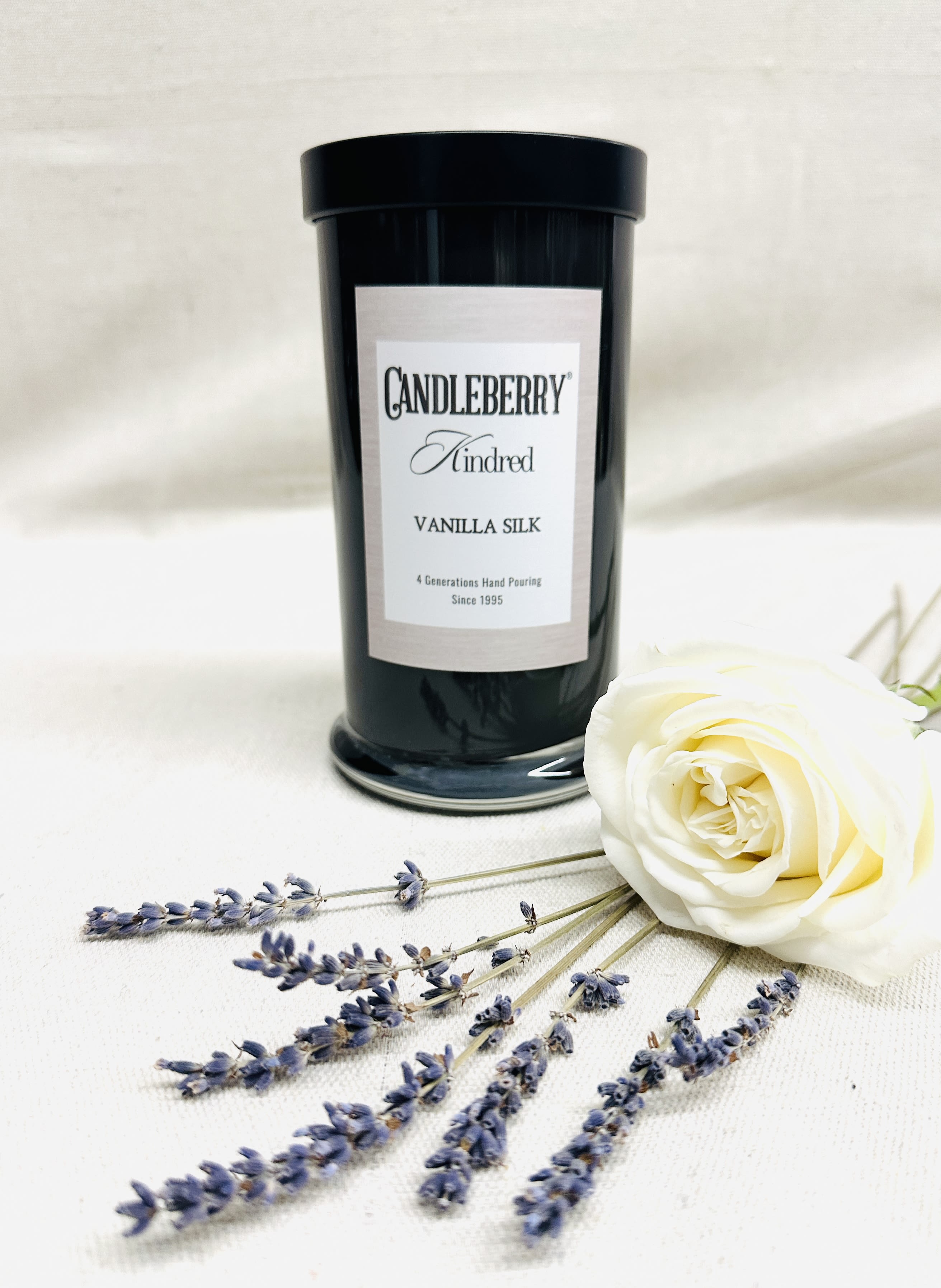 Black candle jar with a white rose and lavender sprigs