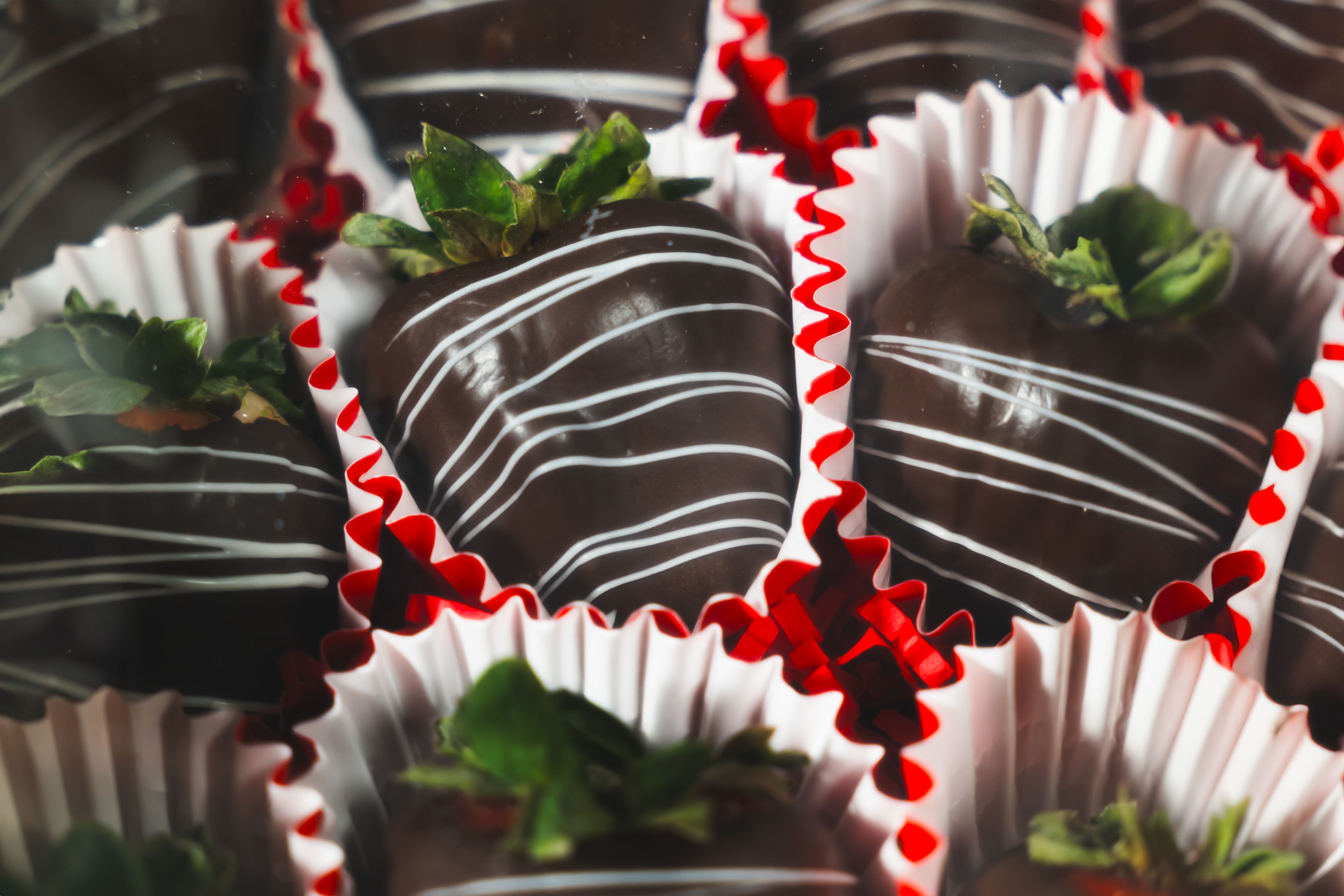Box of chocolate-covered strawberries in red and white paper cups