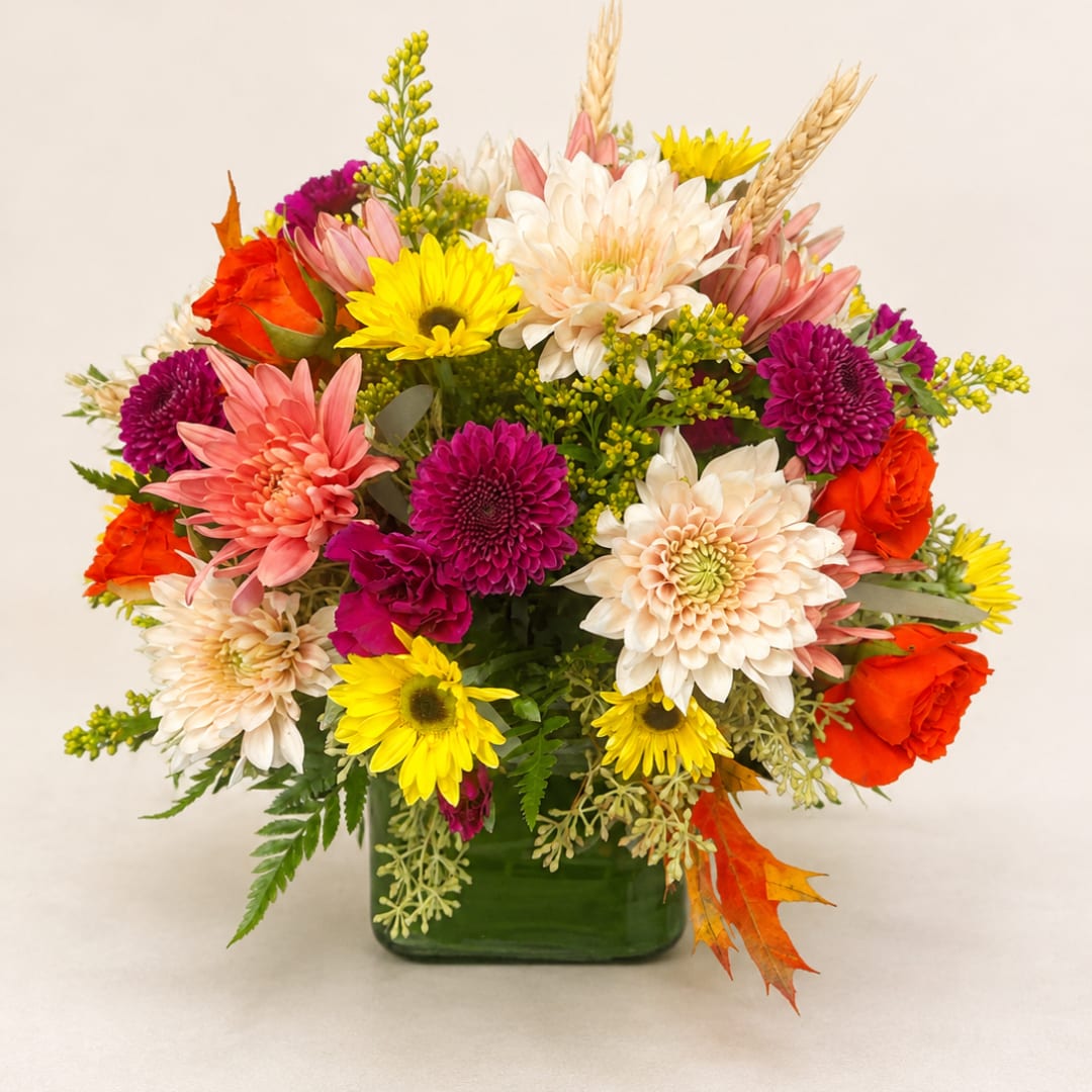 Colorful mixed bouquet in a green glass vase with chrysanthemums and roses