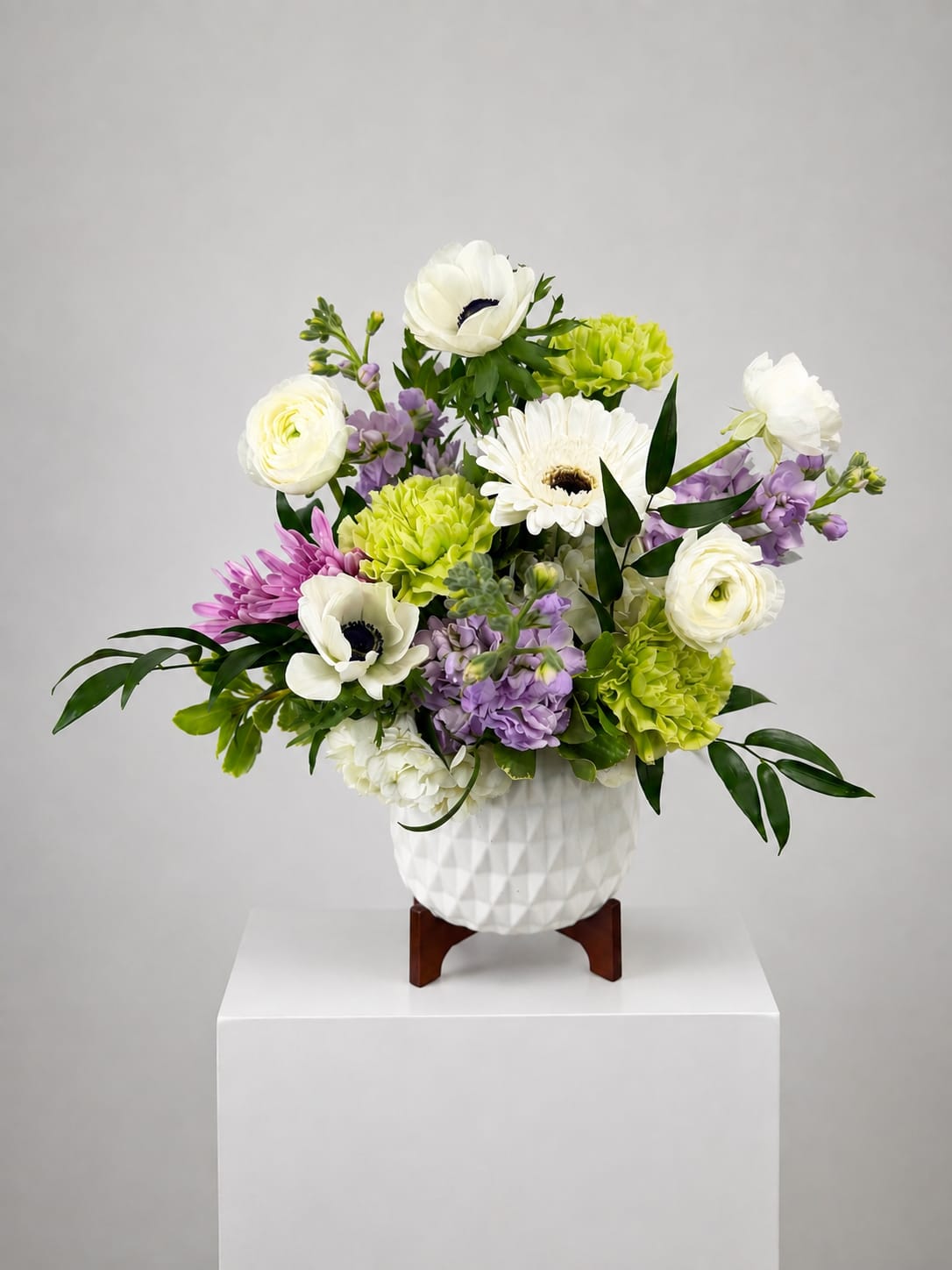 White and lavender floral arrangement in a white textured vase