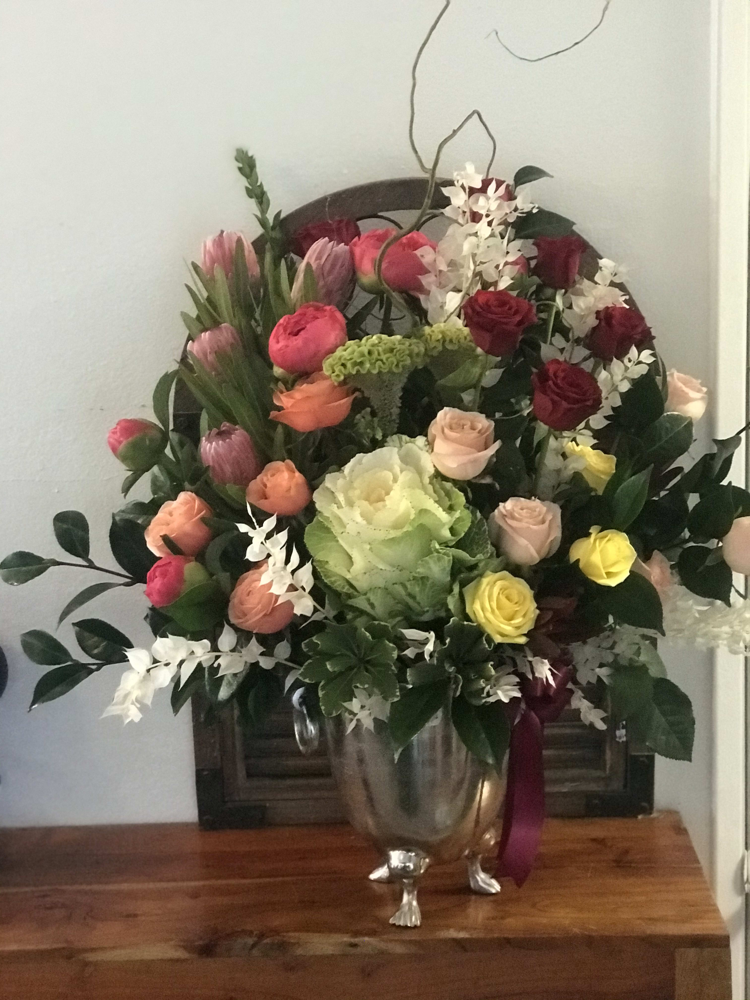 Mixed bouquet of roses, tulips, and orchids in a silver vase