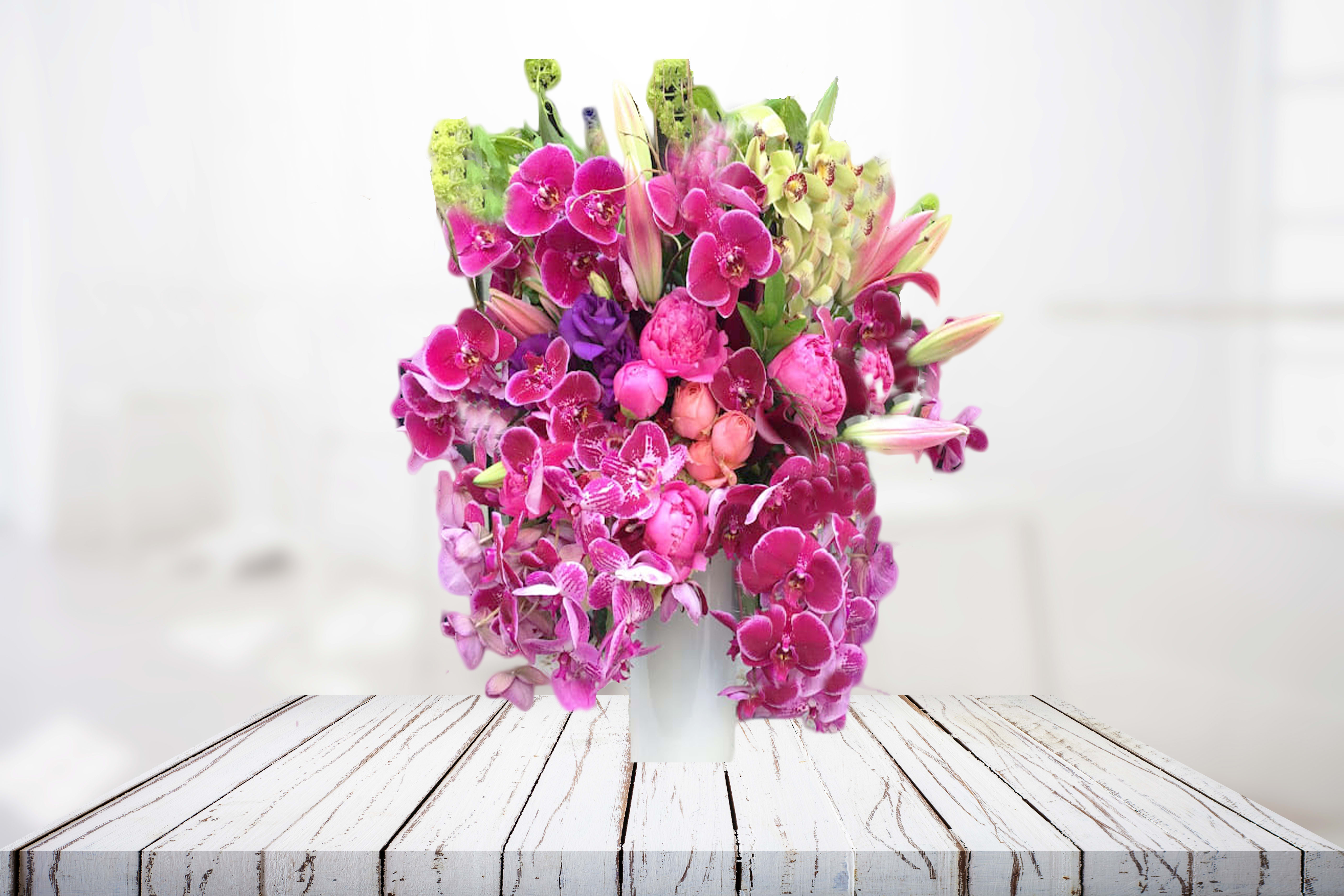 Pink orchid arrangement in a white vase