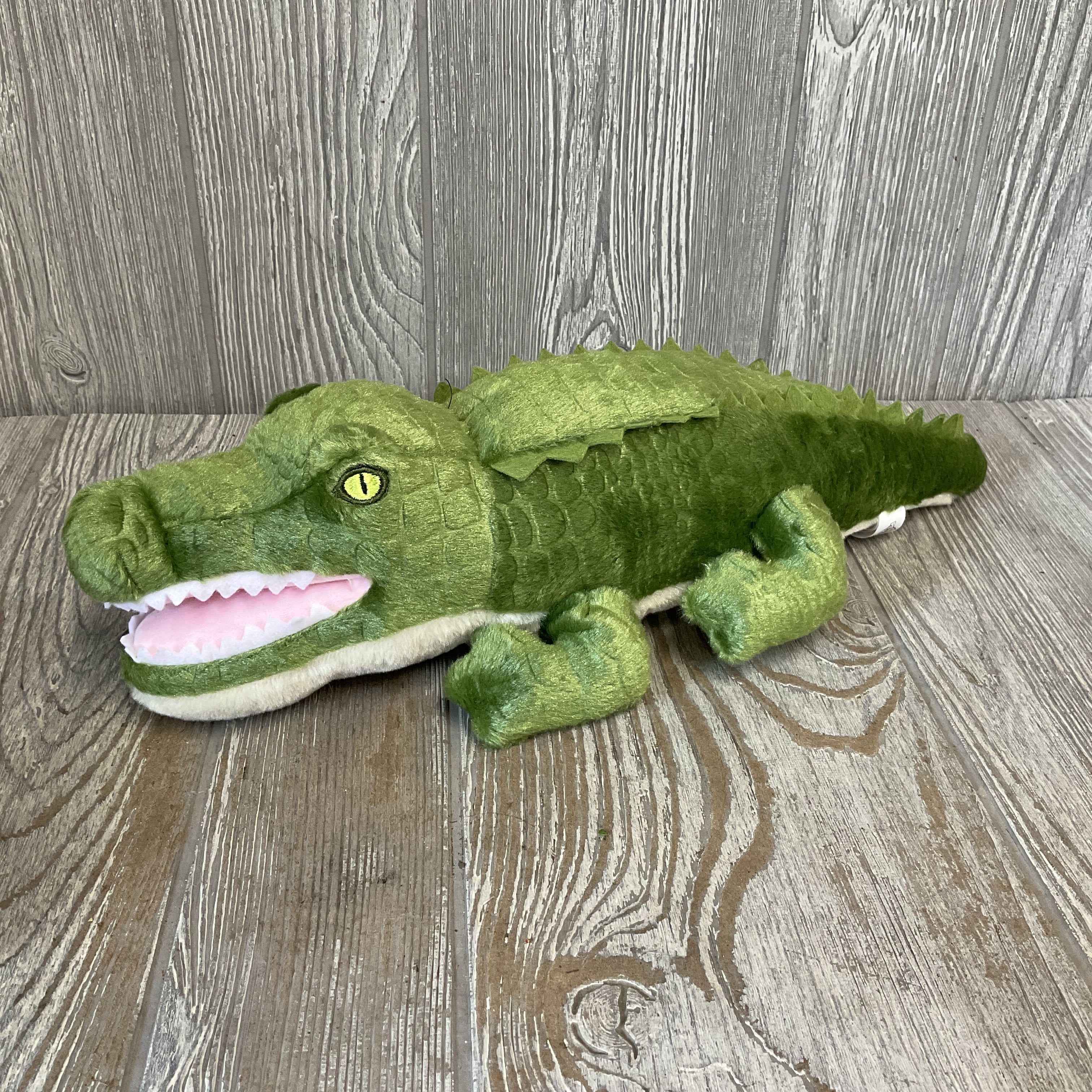 Alligator Plushie 10" Zoologee Earth Keeperz - A bright, playful companion gift that brings a smile-this plush alligator is a cheerful novelty perfect for a child's birthday, a baby shower, or as a whimsical add-on to a floral delivery. As a gift for kids or the kid-at-heart, it signals fun and affection: imagine the recipient's delight at finding this textured green alligator tucked into a bouquet or given as a standalone surprise. Is baby safe and made with recycled materials.  The 10-inch plush features a textured green body with a pale underside, a pink open mouth with white teeth, and a cartoon-like eye for an instantly friendly look. Posed lying flat, it's lightweight and easy to tuck into bouquets, gift baskets, or delivery boxes as a cuddly companion. Durable soft materials make it ready for hugs and play right away.  Perfect as a novelty companion to birthday flowers, baby gifts, or a cheerful "thinking of you" delivery, this alligator is an easy way to make someone feel seen and delighted. Care is simple-spot clean as needed-and its compact size means it arrives ready to charm alongside your floral selection.