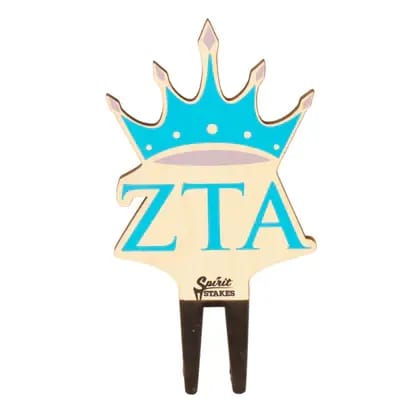 Zeta Tau Alpha Crown Color Plant Stake  - A crown-shaped stake with bold blue ZTA lettering delivers instant sorority pride - perfect as a graduation surprise, chapter gift, or a housewarming accent for the Zeta Tau Alpha member in your life. The graphic, emblematic topper reads as a spirited collegiate display that will make the recipient feel celebrated and seen whether it's placed at a tailgate, in a dorm window box, a plant, or by the front walkway.  This piece is a decorative crown sign cut in a simple silhouette with large blue ZTA letters on a wood background and two dark stake legs for easy placement. The stake is designed to tuck into pots, planters, or soft ground and adds a clean, collegiate pop of color alongside greenery or on its own as a porch or event accent. Its casual, emblematic look makes it an approachable, thoughtful way to say "I'm thinking of you" to grads, alumni, new homeowners, or any devoted sorority fan. Care is minimal-place the stake where it's visible and secure in soil or a planter for long-lasting display.