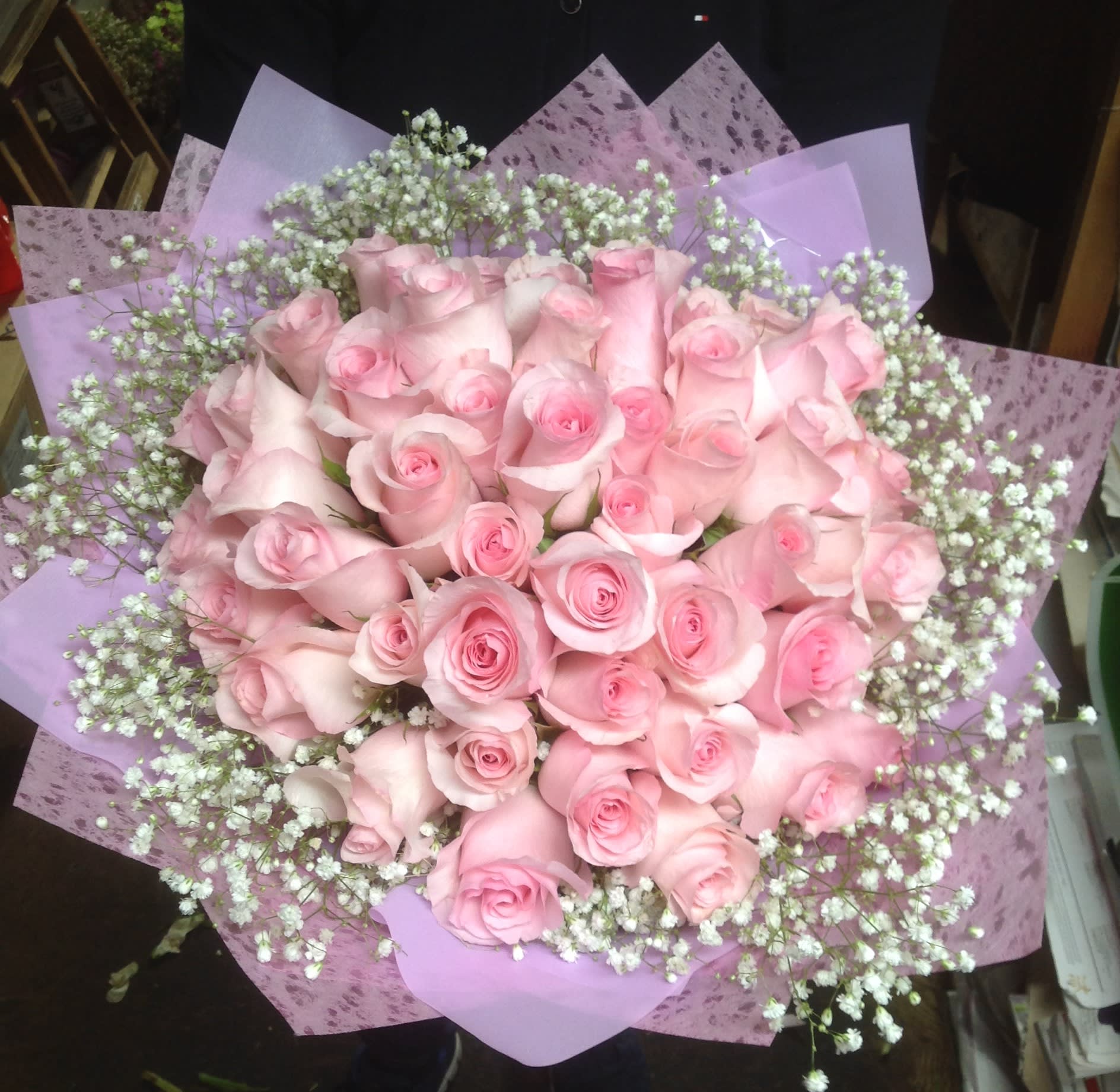 Bouquet of pale pink roses with white baby's breath in lavender wrapping