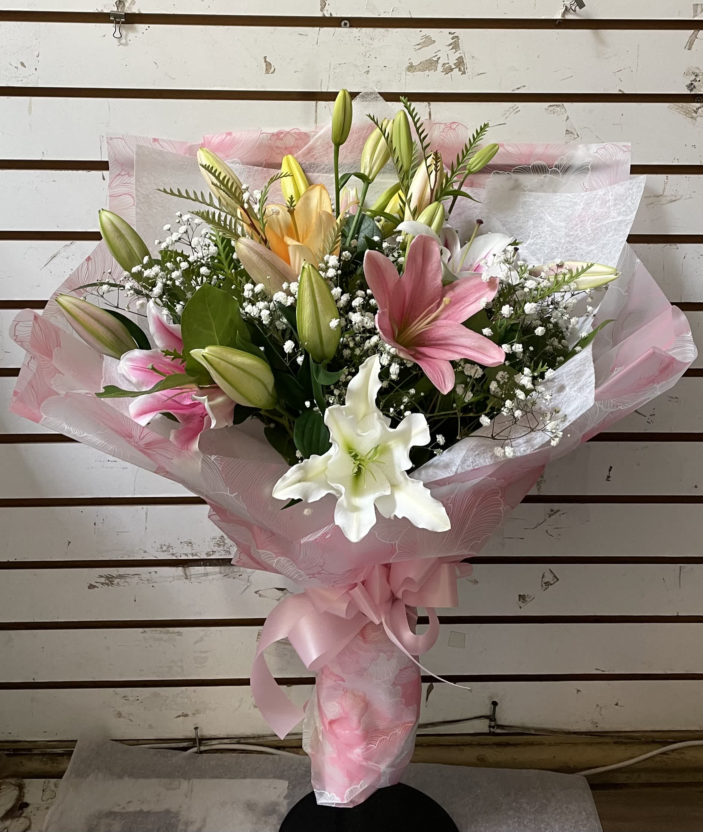 Bouquet of pink, white, and yellow lilies wrapped in pink paper