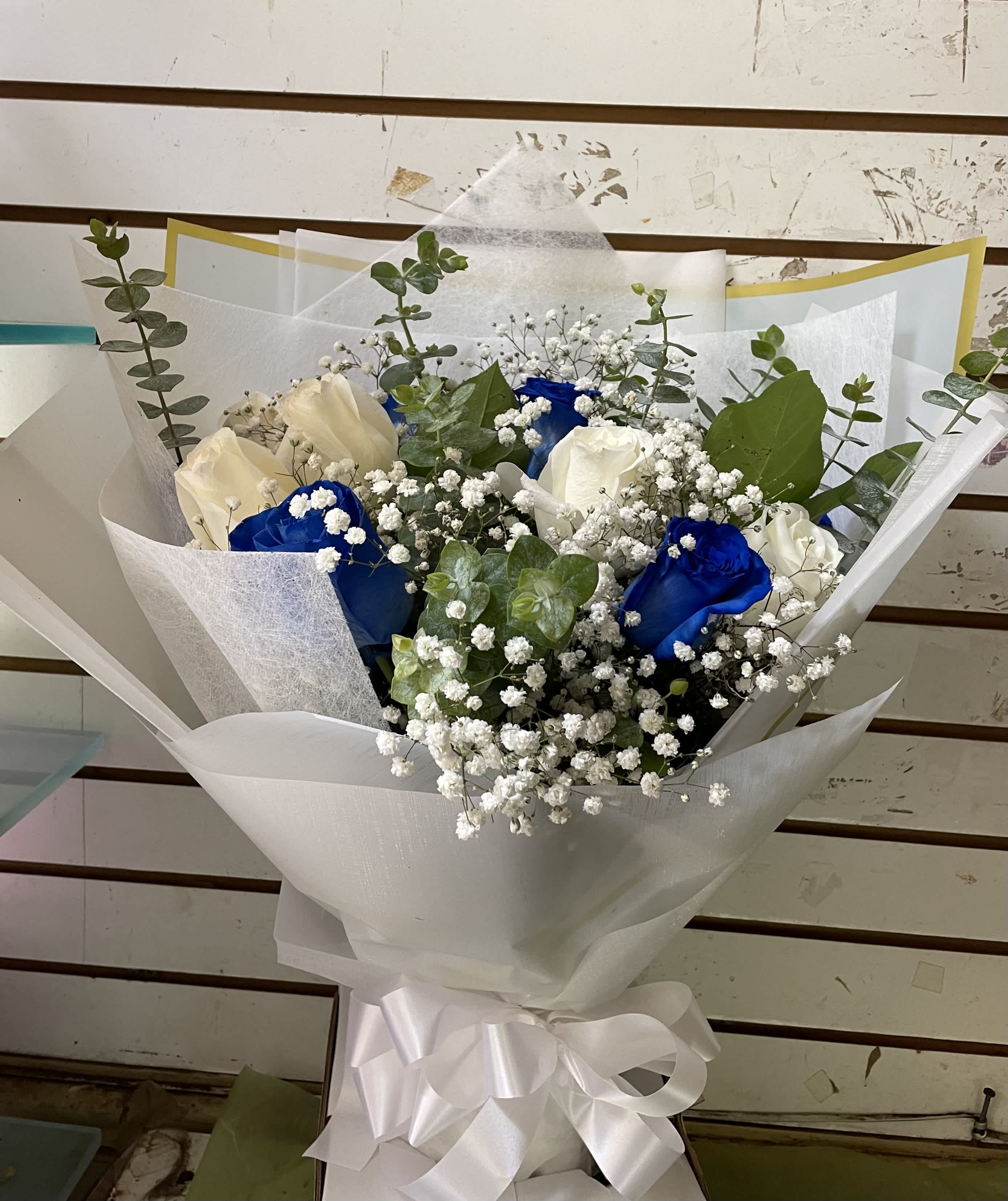 Bouquet of white and blue roses with baby's breath and eucalyptus in white wrap